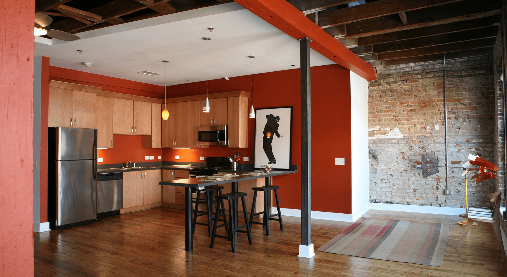a kitchen with red walls, wooden floors and tables