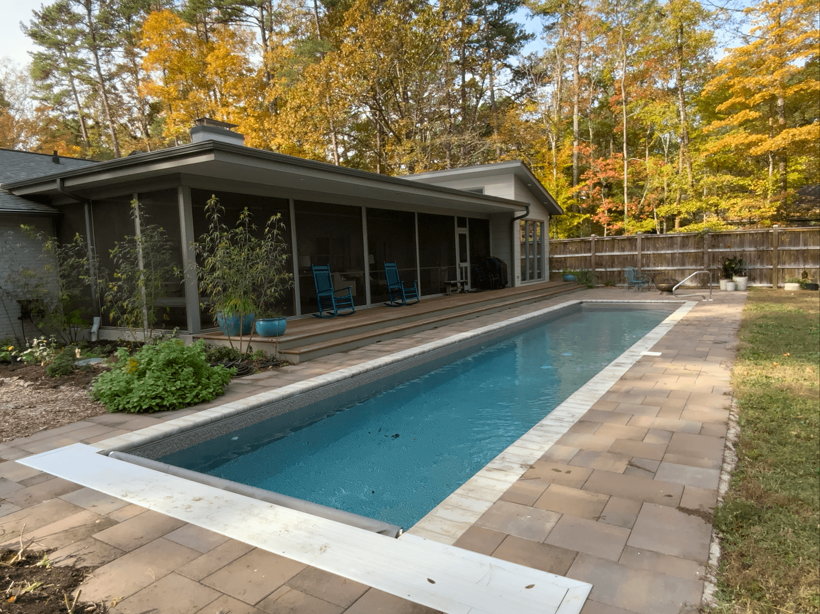 a pool beside a house with trees around it
